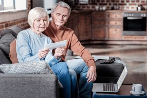 Foto: Älteres Ehepaar auf Couch betrachtet Brief